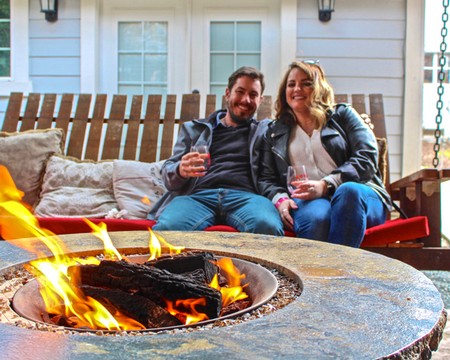 Happy couple enjoying wine by a fire pit in a cozy outdoor space, promoting Lodi winegrapes and local wine culture.