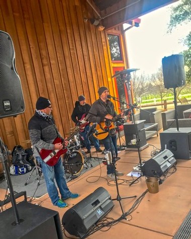 Band performing live music outdoors at Lodi Winegrape Commission event with instruments and sound equipment.