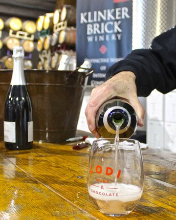 Pouring wine into a glass at a Lodi wine tasting event, showcasing local wine culture and winegrape expertise.