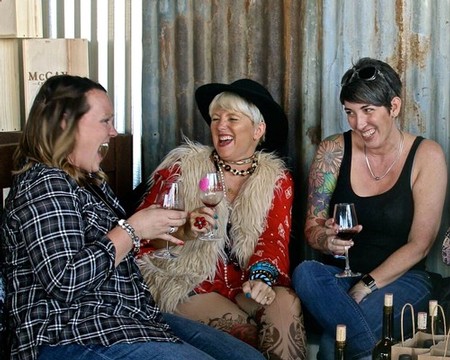 Three women enjoying wine at a Lodi Winegrape Commission event, smiling and engaging in conversation.