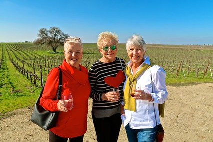Three women enjoying wine tasting at a vineyard in Lodi, California on a sunny day.
