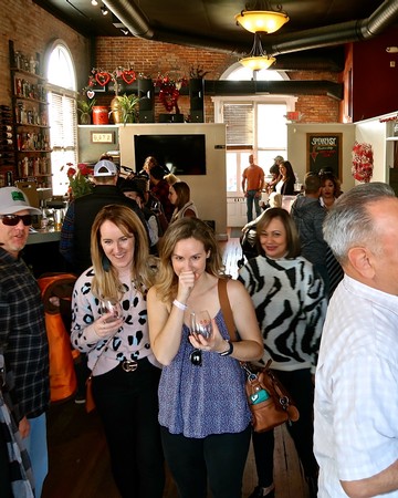 People enjoying wine tasting at Lodi Winegrape Commission event in a rustic indoor setting.