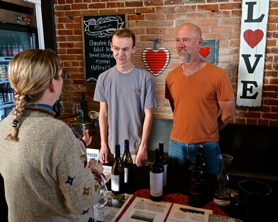 People tasting wine at Lodi Winegrape Commission event with brick wall background and love-themed decor.