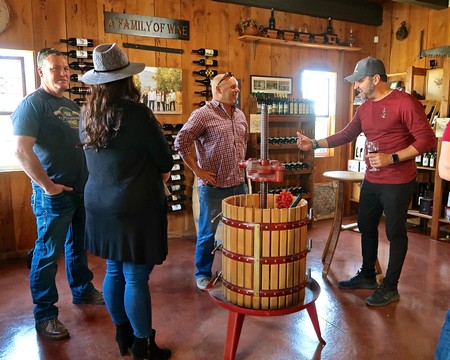 Group of people enjoying wine tasting at Lodi Winegrape Commission with wine bottles and barrels.