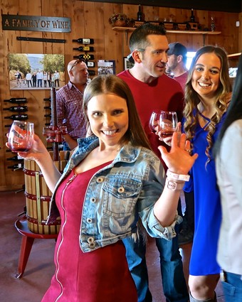 Happy people enjoying wine tasting at Lodi Winegrape Commission event in a cozy winery setting.