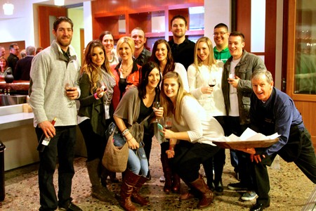 Group of people enjoying wine at Lodi Winegrape Commission event in a modern venue.