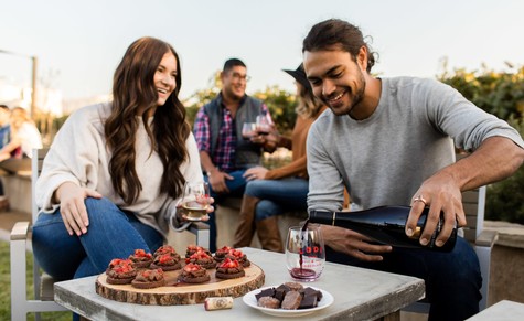 Group enjoying wine and desserts outdoors, showcasing Lodi Winegrape Commission's wine culture and community.