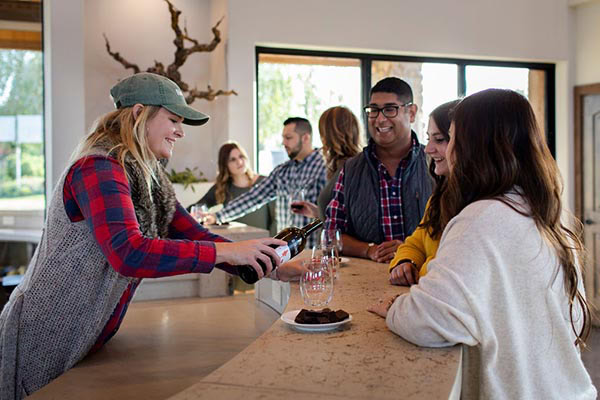 Group of people enjoying wine tasting at Lodi Winegrape Commission event in a modern tasting room.