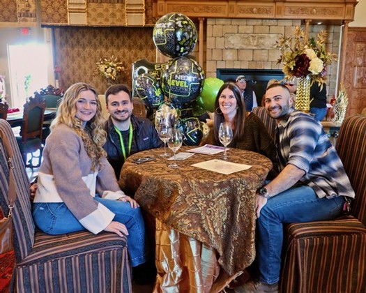 Group of four people celebrating at a table with balloons and flowers, promoting Lodi winegrapes.