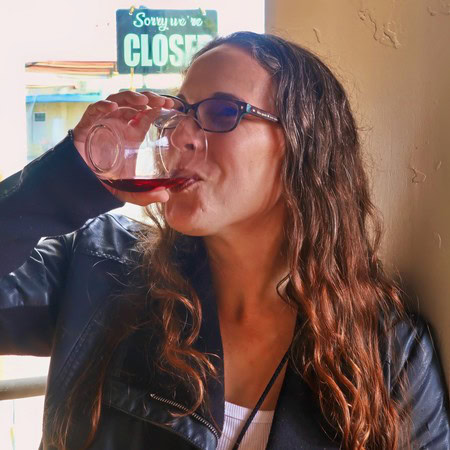 Woman with glasses drinking red wine at Lodi Winegrape Commission event.