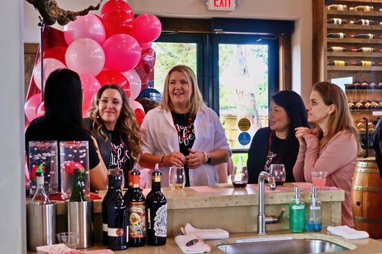 Women enjoying wine tasting at Lodi Winegrape Commission event with balloons and wine bottles.