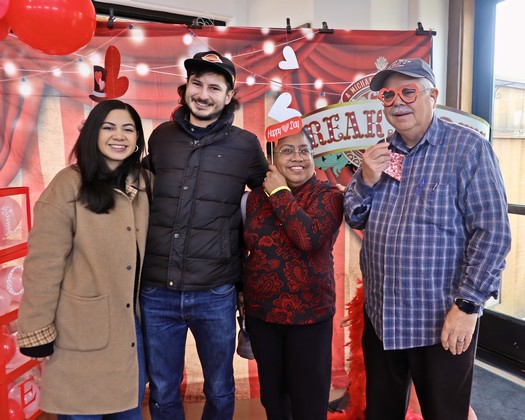 Group of four diverse people celebrating Valentine's Day with decorations and smiles at Lodi Winegrape Commission event.