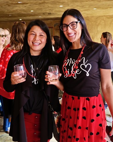 Two women smiling and holding wine glasses at a Lodi Winegrape Commission event.
