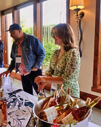 People enjoying wine tasting at a Lodi Winegrape Commission event with bottles on display.