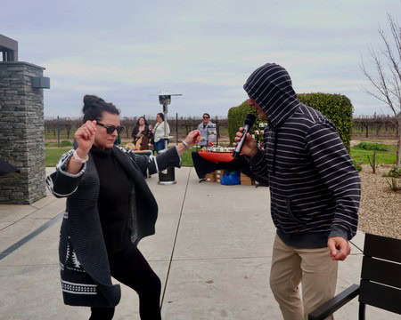 People enjoying music and dancing outdoors at a Lodi wine event with vineyards in the background.
