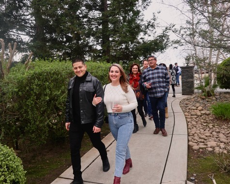 Group of people walking outdoors in a garden, enjoying a wine tasting event in Lodi, California.