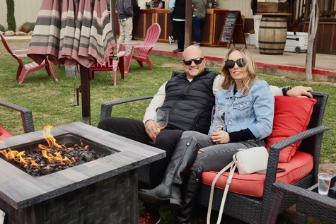 Couple enjoying wine by a fire pit at Lodi Winegrape Commission outdoor event.