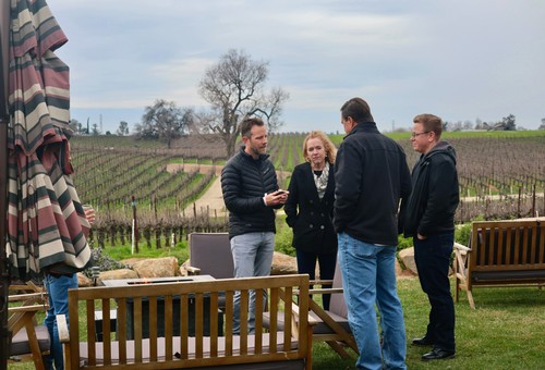 Group of people discussing wine grapes at a vineyard in Lodi, California.