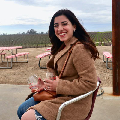 Smiling woman enjoying wine tasting at Lodi Winegrape Commission vineyard in California.