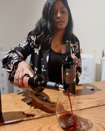 Woman pouring red wine into a glass at a wine tasting event, promoting Lodi winegrapes and wine industry.