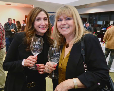 Two women smiling and holding wine glasses at a Lodi Winegrape Commission event.