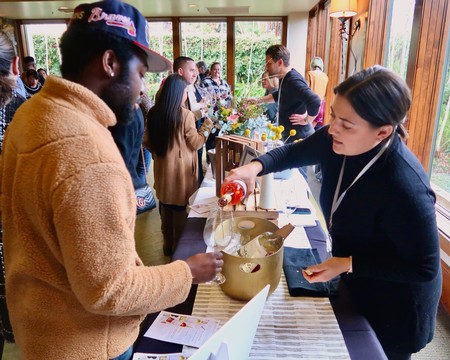 People enjoying wine tasting at Lodi Winegrape Commission event in a cozy indoor setting.