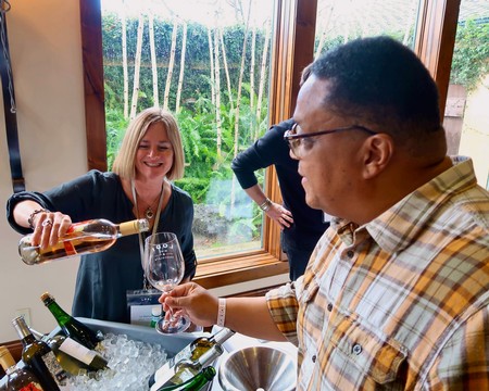 People enjoying wine tasting at Lodi Winegrape Commission with scenic vineyard view.