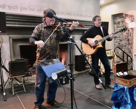 Musicians performing live with guitar and violin at Lodi Winegrape Commission event in a cozy indoor setting.