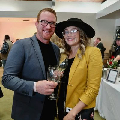 Smiling man and woman at Lodi Winegrape Commission event holding wine glasses.