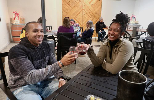 Two friends clinking glasses of red wine at Lodi Winegrape Commission event.