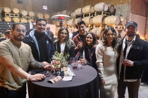Group of people enjoying wine tasting at Lodi Winegrape Commission event in a winery setting.