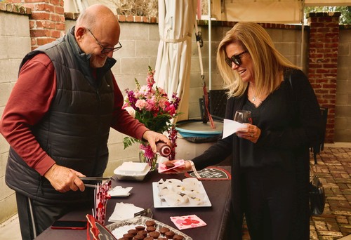 Two women at a wine tasting event, smiling and enjoying wine and chocolates outdoors.