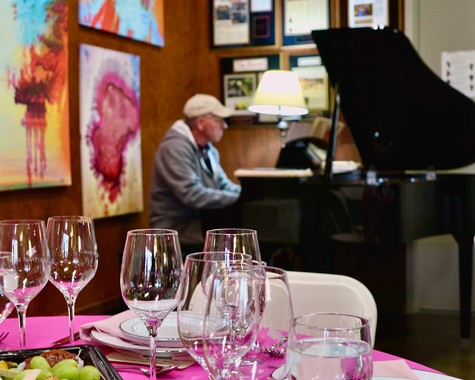 A pianist performs at a Lodi Winegrape Commission event with a table set for wine tasting.
