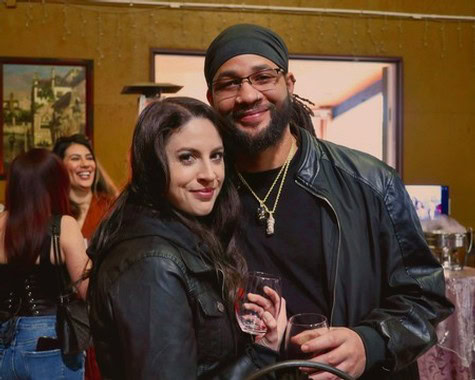 Smiling man and woman holding wine glasses at a wine tasting event.