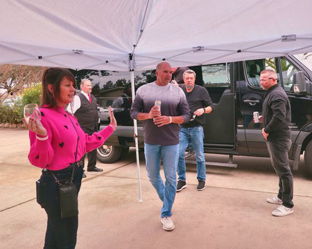Group of people enjoying wine tasting outdoors under a canopy at a Lodi wine event.