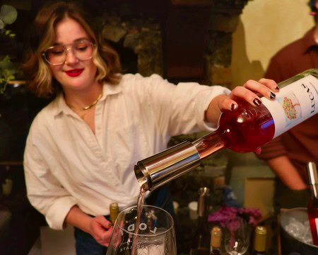 Woman pouring red wine into a glass at a Lodi Winegrape Commission event.