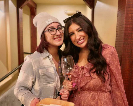 Two women smiling and holding a wine glass at Lodi Winegrape Commission event.