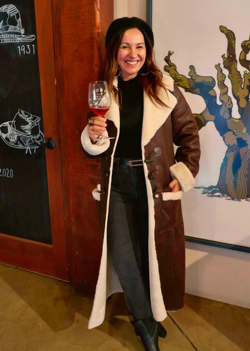 Smiling woman holding a glass of red wine at a Lodi Winegrape Commission event.