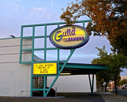 Guild Cleaners storefront with sign and message board in Lodi, California, during daytime.