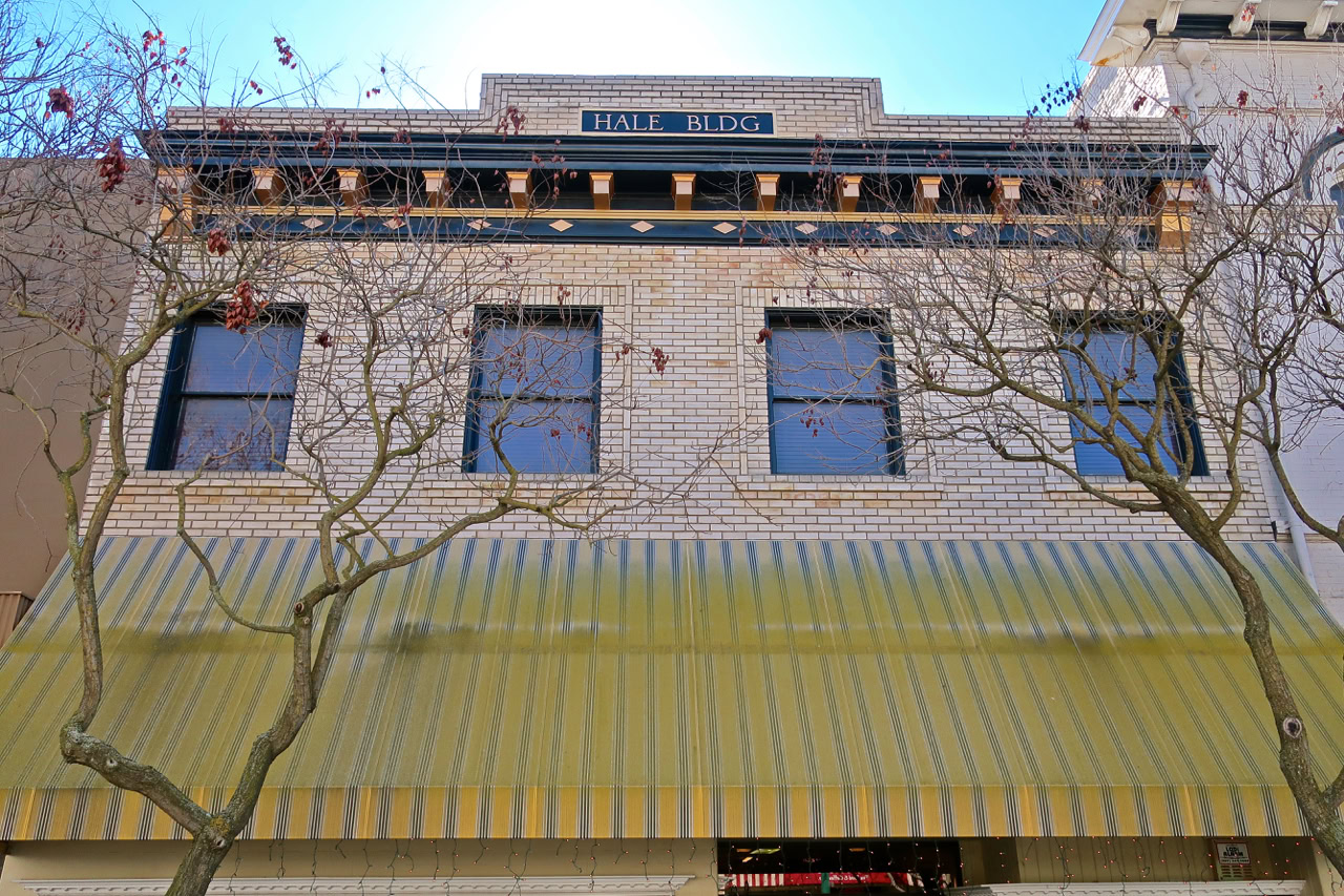Historic Hale Building in Lodi with leafless trees in front and a yellow striped awning.