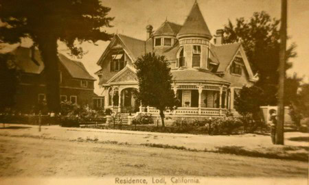 Vintage photo of a large Victorian-style house in Lodi, California, with ornate architecture and surrounding trees.