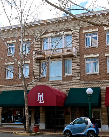 Exterior view of the Lodi Winegrape Commission building with red and green awnings and a Smart car parked outside.