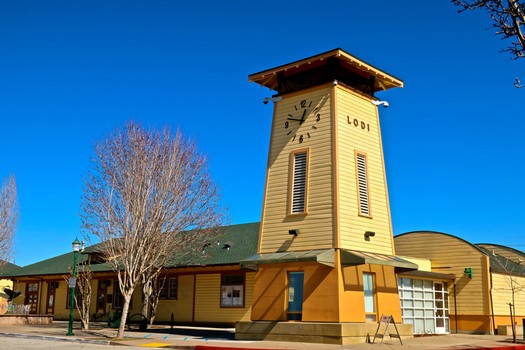 Historic Lodi Winegrape Commission building with clock tower in Lodi, California, under a clear blue sky.