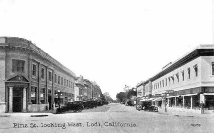 Black and white photo of Pine Street looking west in Lodi, California, with vintage buildings and early 20th-century cars.