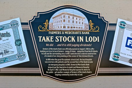 Historical bank sign promoting stock in Lodi with dollar bills on each side.