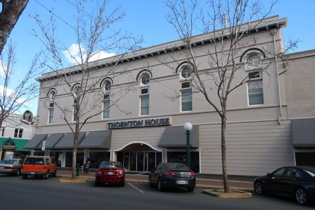 Exterior view of Thornton House, home to the Lodi Winegrape Commission, with parked cars and leafless trees in front.