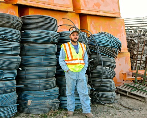 Worker in safety vest standing among coiled cables at construction site for Lodi wine industry.