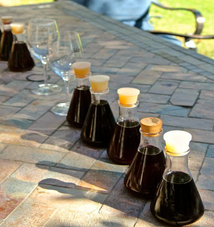 Wine tasting samples from Lodi Winegrape Commission displayed on a stone table outdoors.