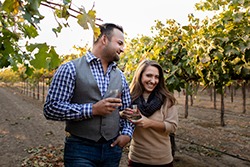 Happy couple enjoying wine tasting in a vineyard during harvest season in Lodi, California.