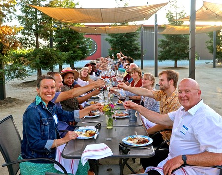Group of people enjoying outdoor dinner at Lodi Winegrape Commission event with wine and food.